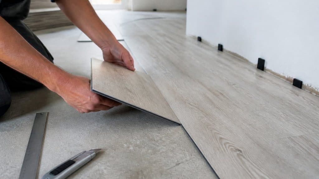 Pose de lames PVC clipsables sur un support en béton préparé, avec cale de dilatation le long du mur