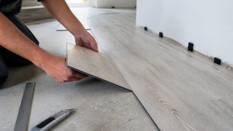 Pose de lames PVC clipsables sur un support en béton préparé, avec cale de dilatation le long du mur