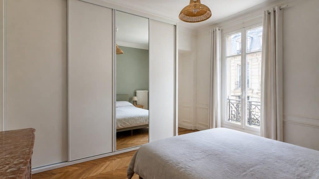 Placard avec porte coulissante dans une chambre lumineuse, illustrant le choix entre porte coulissante, battante et pliante