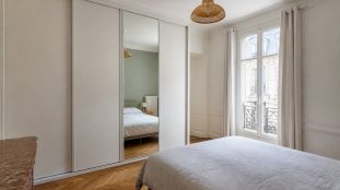 Placard avec porte coulissante dans une chambre lumineuse, illustrant le choix entre porte coulissante, battante et pliante